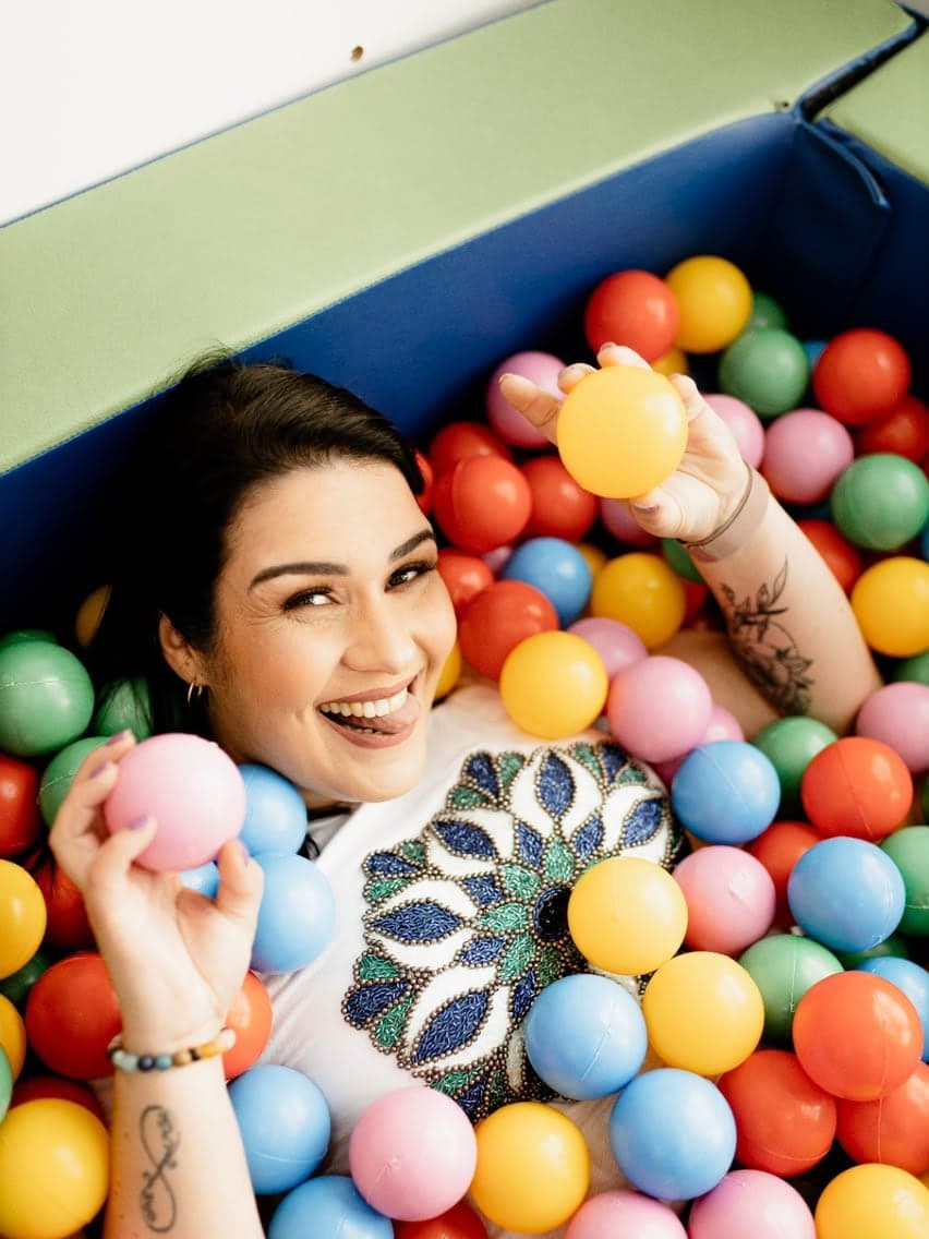 Carolina Almeida sorrindo em uma piscina de bolinhas colorida, equipamento usado em atividades de integração sensorial.